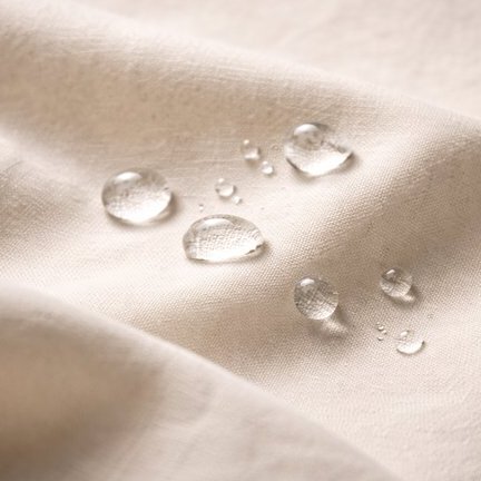 Cream cotton fabric with perfect water beads sitting on a water-repellent finish.